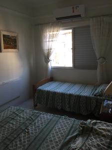 een slaapkamer met 2 bedden en een raam bij Apartamento Astúrias 2 Dorms Ar Cond in Guarujá