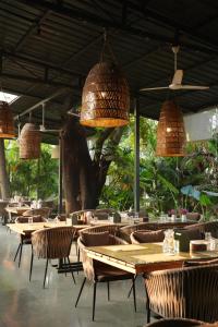 a restaurant with wooden tables and chairs and lights at Oceanature Alibaug in Alibaug
