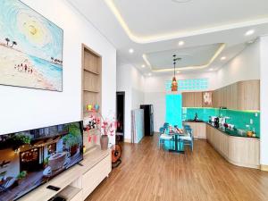 a living room with a large tv and a kitchen at ECHO VILLA PHAN THiET in Phan Thiet