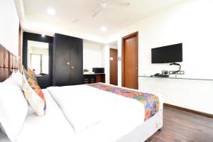 a bedroom with a white bed and a flat screen tv at S R Rooms in Pune