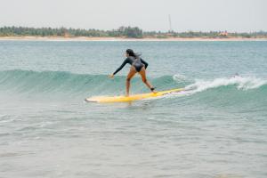 a woman riding a wave on a surfboard in the ocean at Robbo's Surfcamp in Arugam Bay