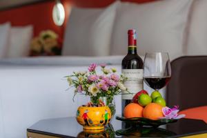 a bottle of wine and a vase with flowers and fruit at Sono Sallute Luxury Hotel in Ho Chi Minh City
