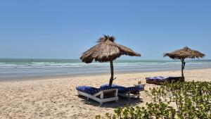 two umbrellas and chairs on a beach with the ocean at Terema Lodge in Kanuma