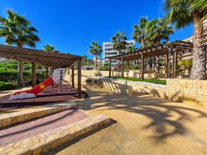 a playground with a slide in a park with palm trees at Beachfront Luxury Apartments by NRAS in Arenales del Sol
