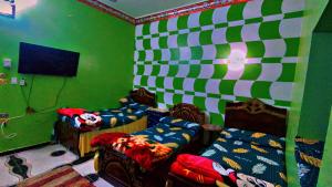 a green and white room with two beds and a tv at The white House in Aswan