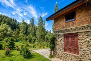 a stone house with a red door and a garden at Shepherd Barn Pahalgam in Pahalgām