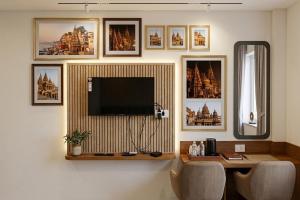 a room with a television on a wall with pictures at Hotel Banaras Vandanam in Varanasi