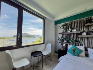 a bedroom with a large window and a bed and chairs at maisonde ojolac in Kosŏng-ni