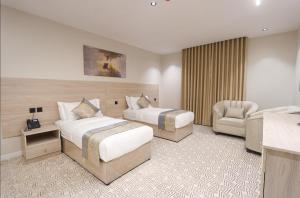 a hotel room with two beds and a chair at فندق سويتس لاين in Medina