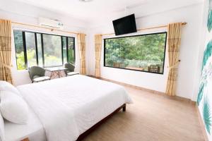 a bedroom with a white bed and a large window at Thao Nguyen Homestay in Phong Nha