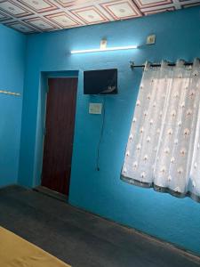 a room with a blue wall with a window and a door at Bhudda Lodge in Tirupati +4 photos