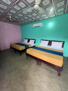 two beds in a room with blue and green walls at Bhudda Lodge in Tirupati