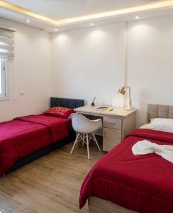 a bedroom with two beds and a desk with a chair at Résidence Nour in Monastir