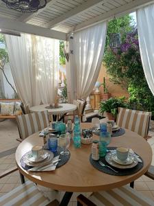 a wooden table with plates and cups on a patio at Domos Le Due Tuie in Piscinas