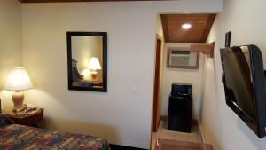 a room with a bed and a television and a mirror at Atlantic Motel in Point Pleasant Beach