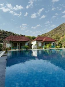 a villa with a swimming pool and a house at Orchard Hills Resorts in Pushkar