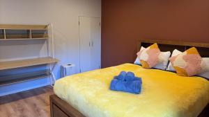 a yellow bed with two blue gloves on it at Ke's home in Wellington
