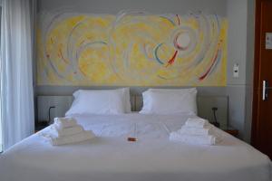 a bed with towels on it with a painting on the wall at Hotel Luna in Sirmione