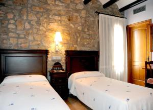 a bedroom with two beds and a stone wall at Hotel Restaurante Verdia in Sueras