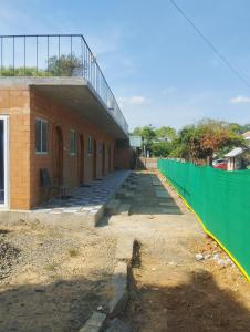 a brick building with a green fence around it at Auro Waves Rooms & Hostel in Auroville