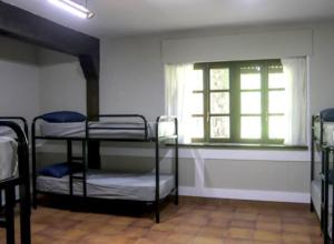 a room with three bunk beds and a window at Albergue Gerekiz AMAGI, exclusivo peregrinos in Flores