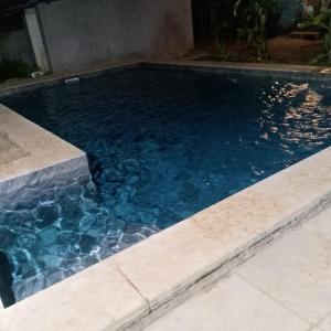 a swimming pool with blue water in a yard at Auro Waves Rooms & Hostel in Auroville