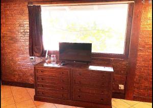 a wooden dresser with a television on it in front of a window at Small Paradise Palermo in Palermo
