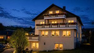 a large white building with flowers on a balcony at Pension Central Ferienwohnungen in Bad Endbach