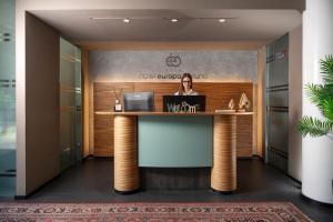 a woman standing at a reception desk in a lobby at Hotel Europa Belluno in Belluno