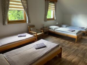 a room with three beds and a chair and two windows at Chata pod Jasanem in Dolní Morava