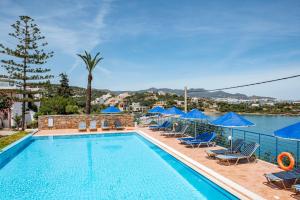 a swimming pool with lounge chairs and blue umbrellas at Poppy Villas in Agios Nikolaos