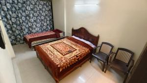 a bedroom with two beds and a chair in it at Salas Executive in Mahabaleshwar