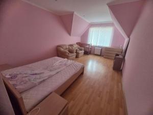 a bedroom with pink walls and a bed and a chair at Full relax in Zatoka
