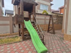 a green slide next to a wooden play house at Full relax in Zatoka