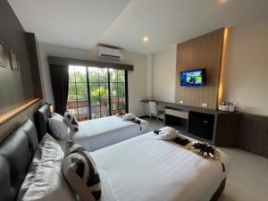 a hotel room with two beds and a flat screen tv at The Room Boutique Hotel in Sakon Nakhon