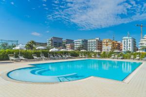 a swimming pool with chairs and buildings in the background at Albamarina Residence in Sottomarina