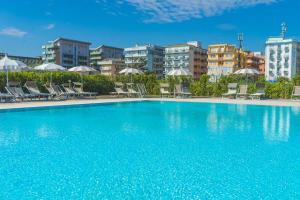 a large swimming pool with chairs and umbrellas at Albamarina Residence in Sottomarina