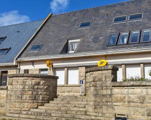 a house with a stone wall and a building at Macleo proche plage in Plougasnou