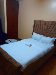a bed with white sheets and pillows in a room at Sifa Stays in Ongata Rongai 