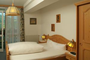 una camera da letto con un letto con lenzuola bianche e due lampade di Appartement & Aparthotel Stern a Imst