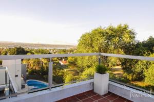 uma varanda com vista para uma piscina e árvores em Posada del Vaivén em Villa Carlos Paz