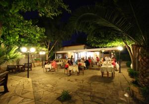 a group of people sitting at a restaurant at night at Hilltop Chalet in Pissouri