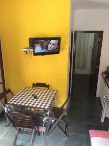 a tv on a yellow wall with a table in a room at Apartamento em Condomínio Praia de Boiçucanga Litoral Norte in Boicucanga