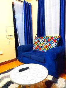 a living room with a blue couch and a table at Sifa Stays in Ongata Rongai 