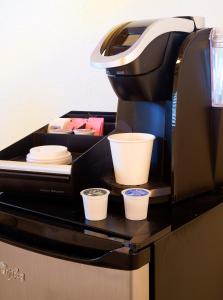 una macchinetta del caffè con tre tazze sul bancone di Atlantic Hideaway a Delray Beach
