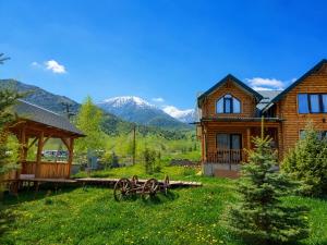 a wooden house with mountains in the background at Мурас Эко - Ресорт in Alamedin