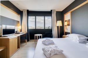 a hotel room with a bed and a desk and a television at Hotel Barcelona Universal in Barcelona