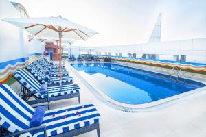 a pool with chairs and an umbrella next to a swimming pool at Grand Excelsior Hotel - Bur Dubai in Dubai
