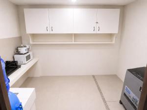 a kitchen with white cabinets and a microwave at Sparrow Transient Townhouse in Davao City +1 photo