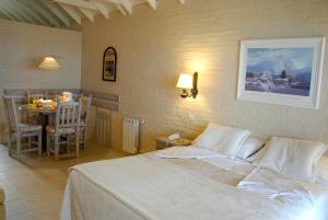 1 dormitorio con cama blanca, mesa y comedor en Carilo Soleil By HS en Cariló